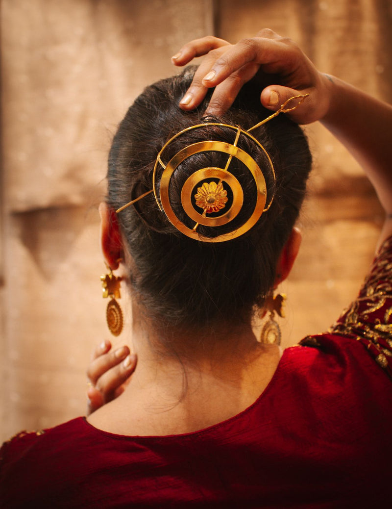 Gold spiral hairbun with concentric circles and intricate design. Elegant and artistic, it conveys a sense of sophistication.