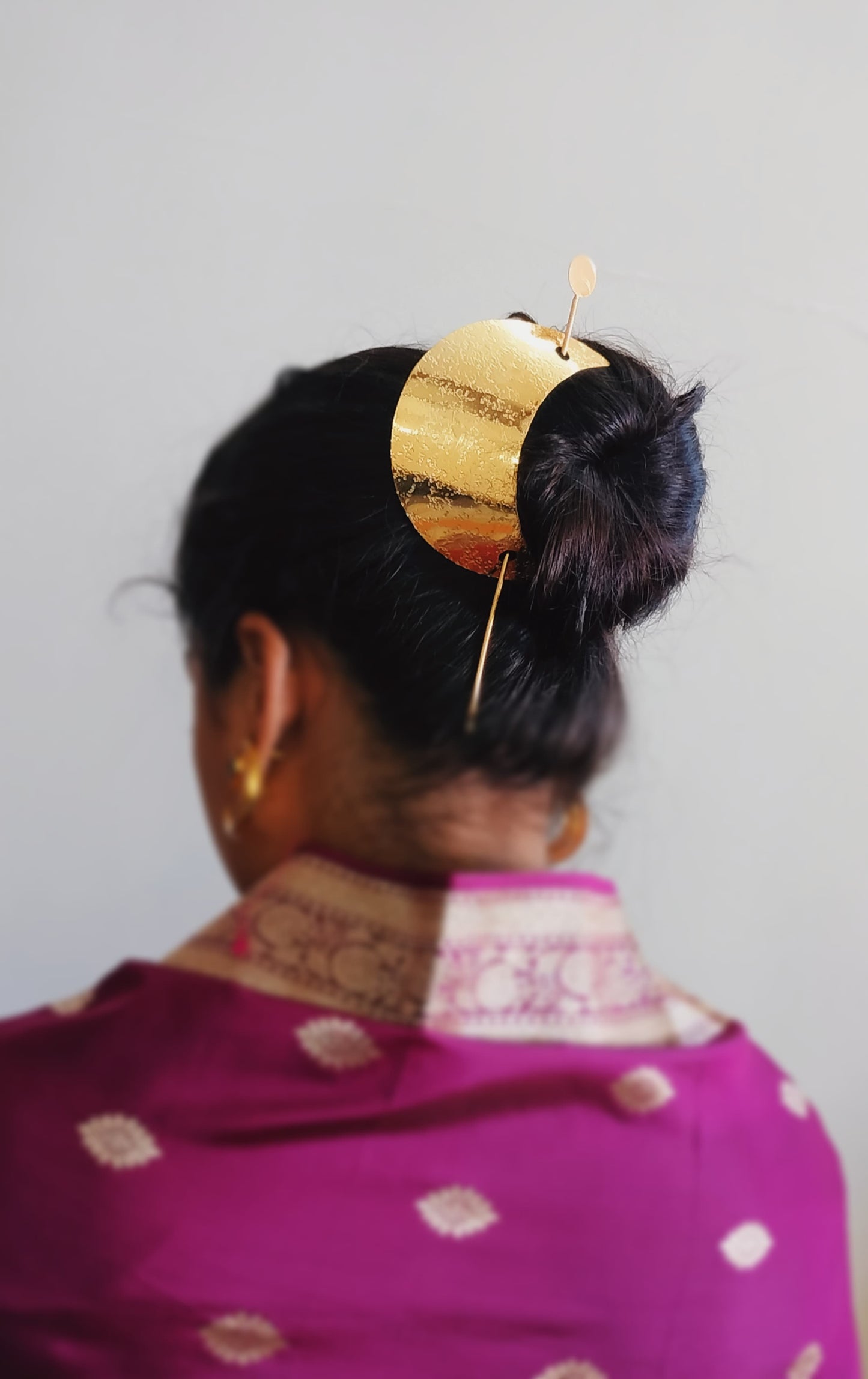 Gold spiral hairbun with concentric circles and intricate design. Elegant and artistic, it conveys a sense of sophistication.