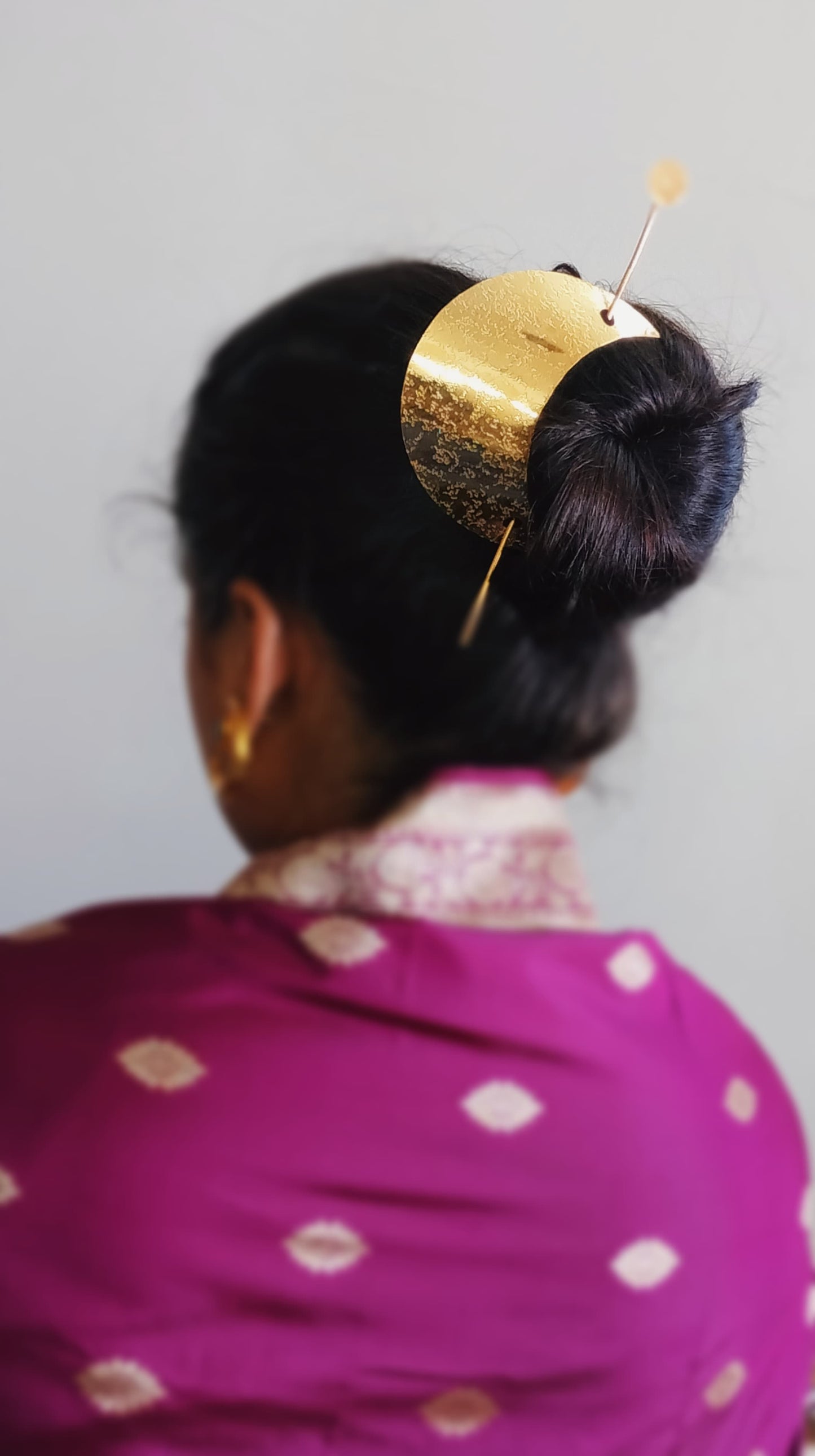 Gold spiral hairbun with concentric circles and intricate design. Elegant and artistic, it conveys a sense of sophistication.