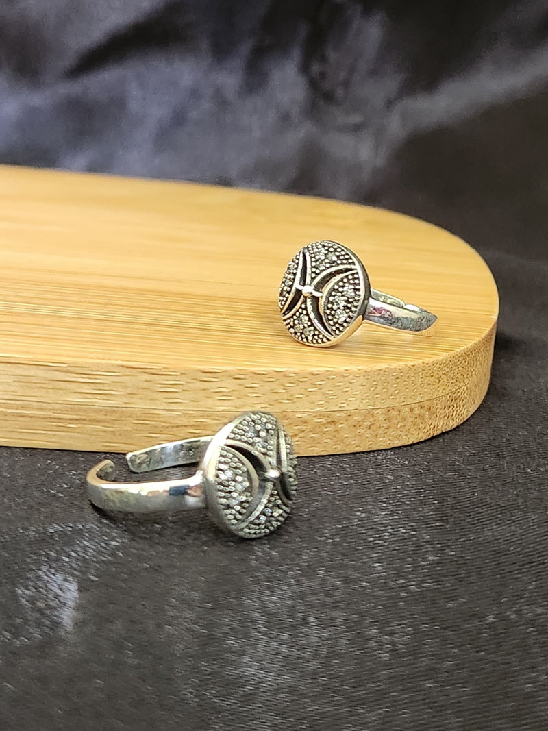 A pair of elegant silver toe rings with a polished finish, featuring delicate designs and an adjustable open band.