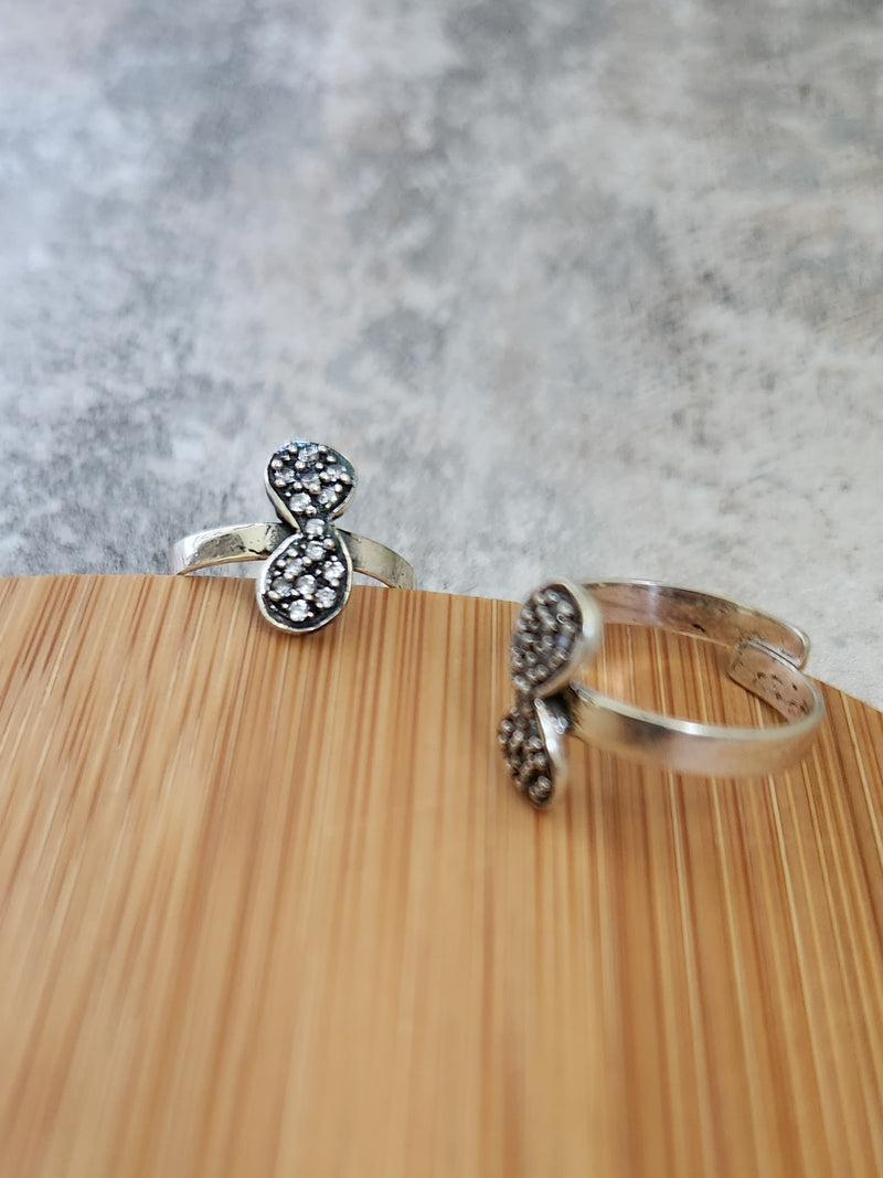 A pair of elegant silver toe rings with a polished finish, featuring delicate designs and an adjustable open band.