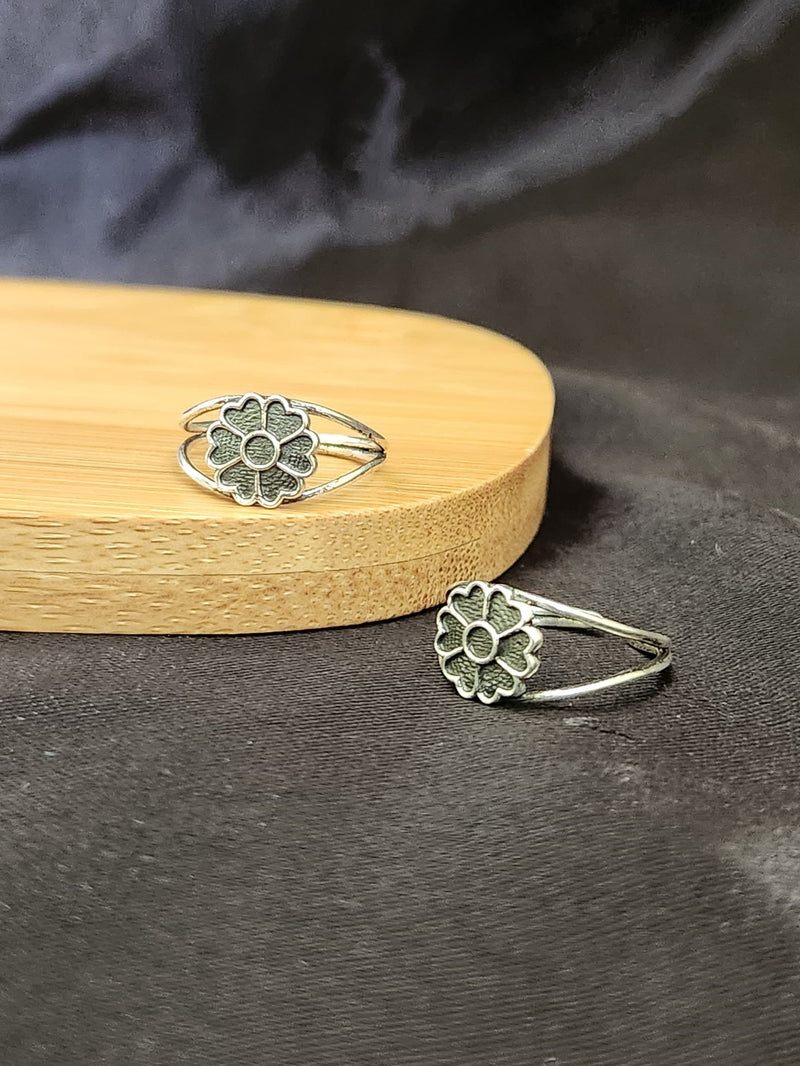 A pair of elegant silver toe rings with a polished finish, featuring delicate designs and an adjustable open band.