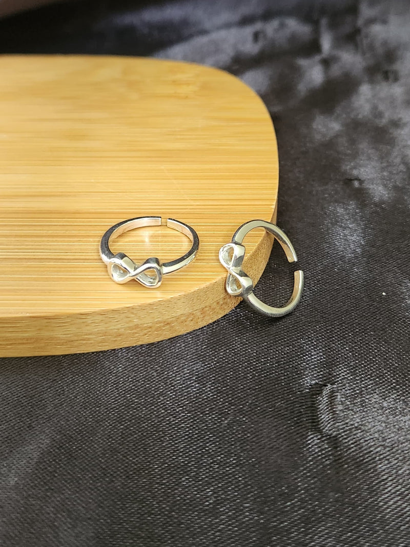 A pair of elegant silver toe rings with a polished finish, featuring delicate designs and an adjustable open band.