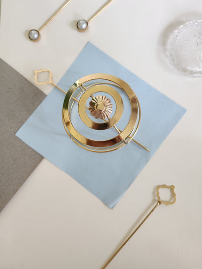 Gold spiral hairbun with concentric circles and intricate design. Elegant and artistic, it conveys a sense of sophistication.