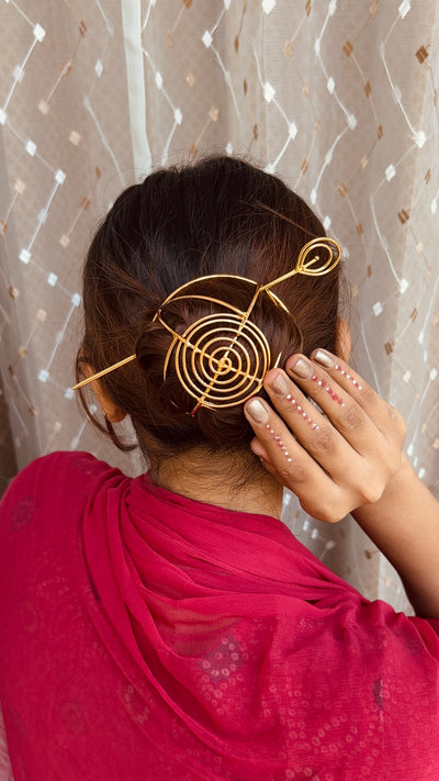 Gold spiral hairbun with concentric circles and intricate design. Elegant and artistic, it conveys a sense of sophistication.