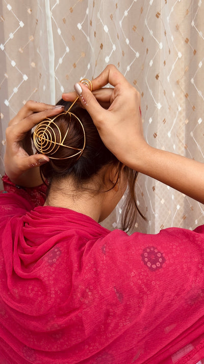 Gold spiral hairbun with concentric circles and intricate design. Elegant and artistic, it conveys a sense of sophistication.