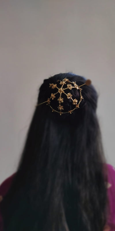 Gold spiral hairbun with concentric circles and intricate design. Elegant and artistic, it conveys a sense of sophistication.