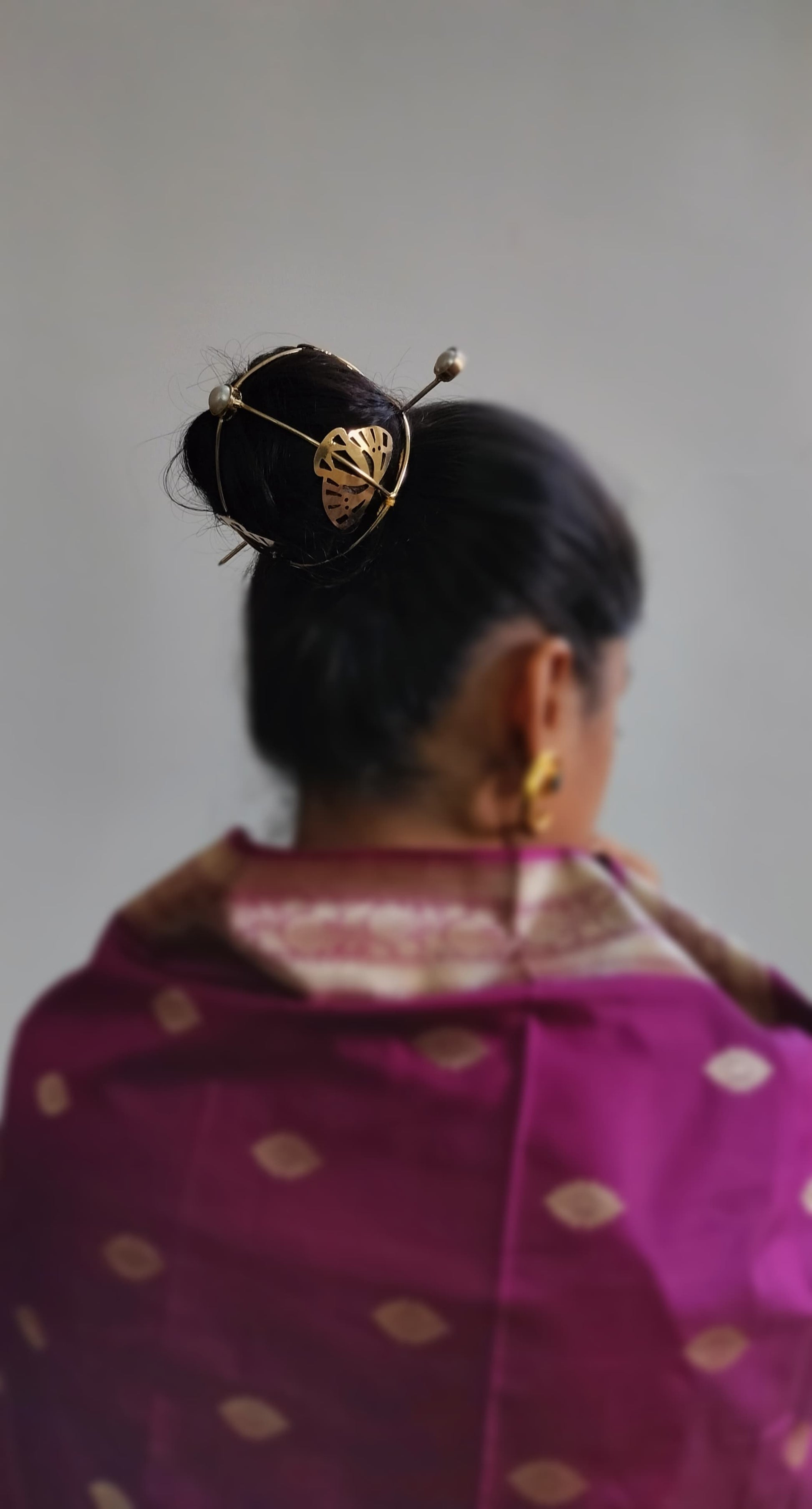 Gold spiral hairbun with concentric circles and intricate design. Elegant and artistic, it conveys a sense of sophistication.