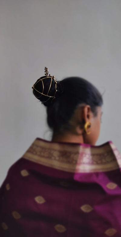 Gold spiral hairbun with concentric circles and intricate design. Elegant and artistic, it conveys a sense of sophistication.