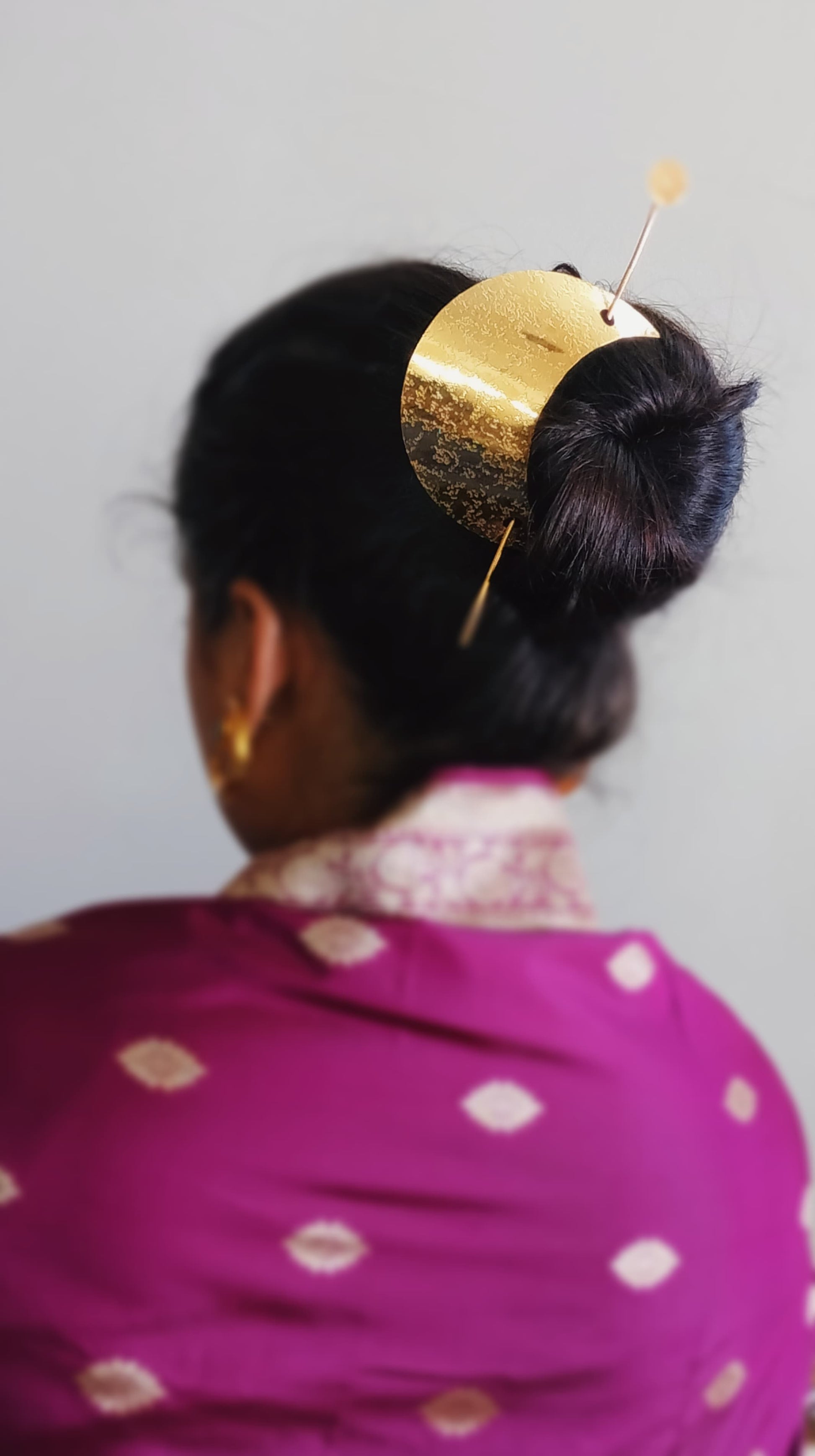 Gold spiral hairbun with concentric circles and intricate design. Elegant and artistic, it conveys a sense of sophistication.