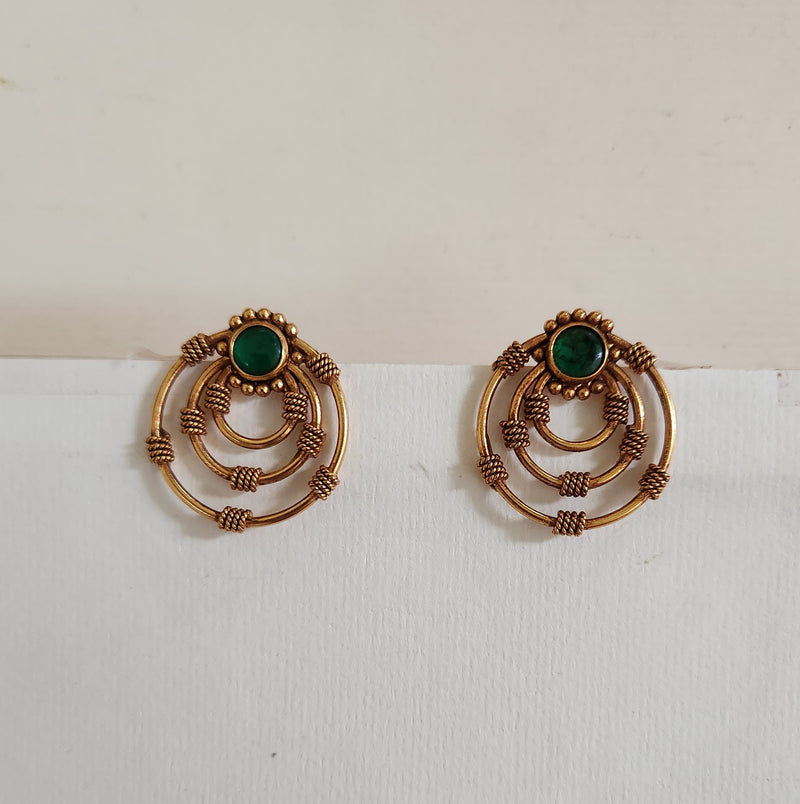 A pair of silver earrings with intricate designs and a central green gemstone, displayed against a white background.