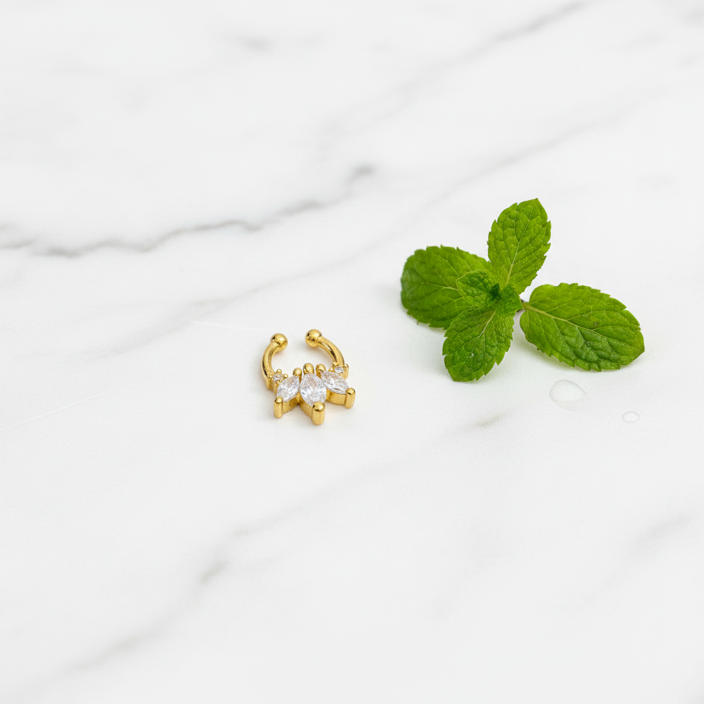 Gold-plated septum nosepin on white marble with fresh mint