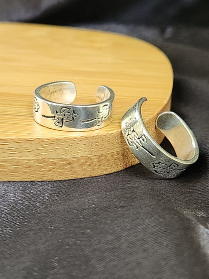 A pair of elegant silver toe rings with a polished finish, featuring delicate designs and an adjustable open band.