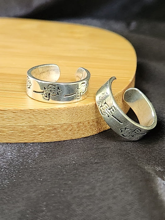 A pair of elegant silver toe rings with a polished finish, featuring delicate designs and an adjustable open band.