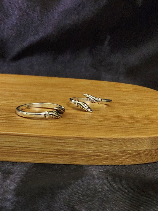 A pair of elegant silver toe rings with a polished finish, featuring delicate designs and an adjustable open band.