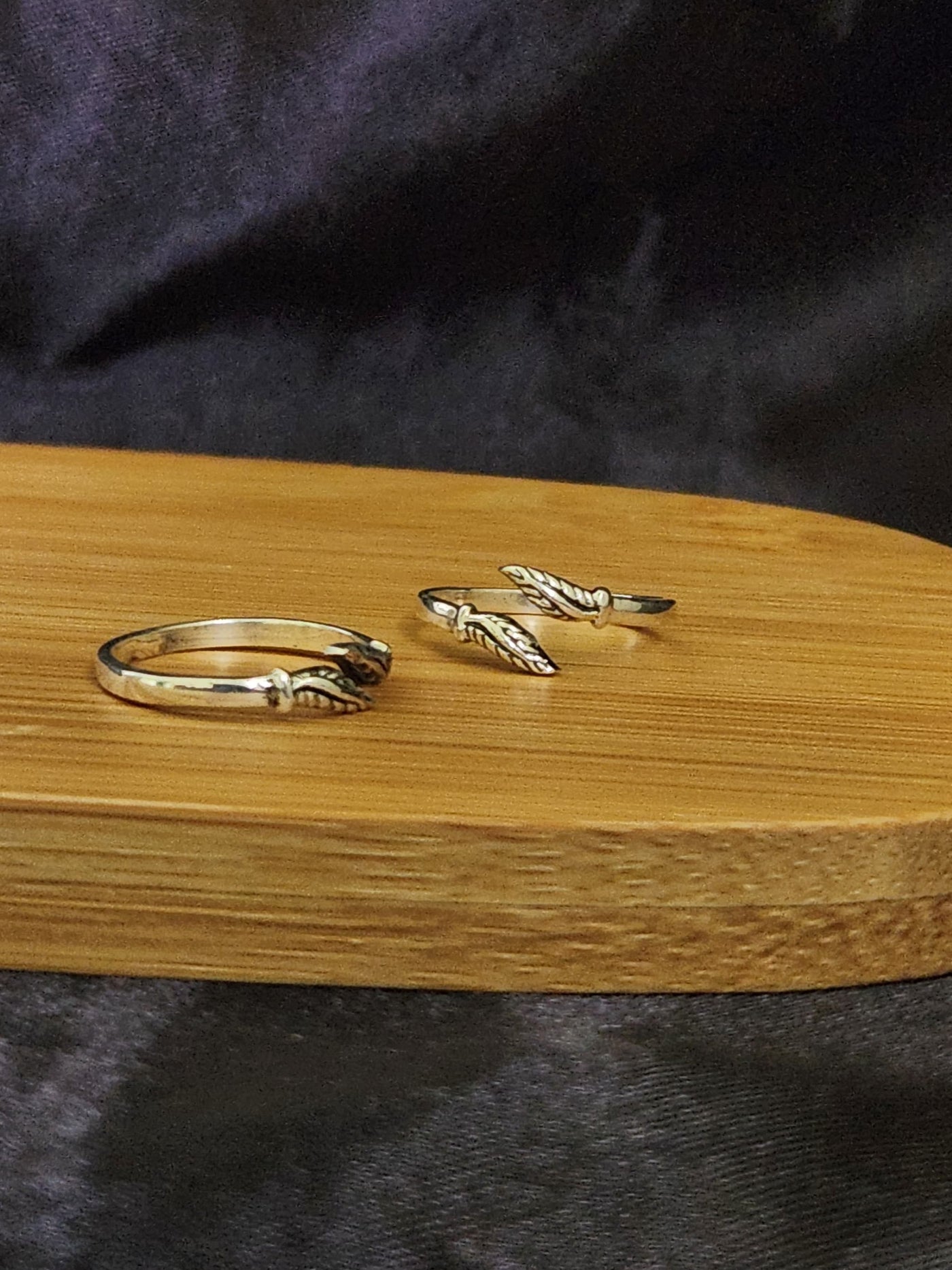 A pair of elegant silver toe rings with a polished finish, featuring delicate designs and an adjustable open band.
