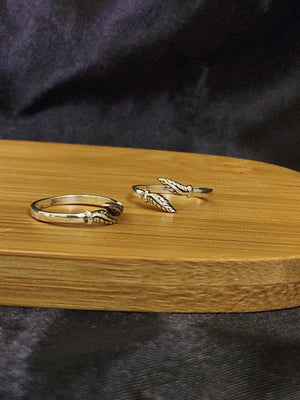A pair of elegant silver toe rings with a polished finish, featuring delicate designs and an adjustable open band.