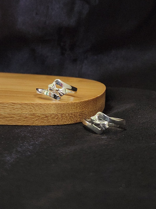 A pair of elegant silver toe rings with a polished finish, featuring delicate designs and an adjustable open band.