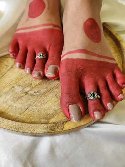 A pair of elegant silver toe rings with a polished finish, featuring delicate designs and an adjustable open band.