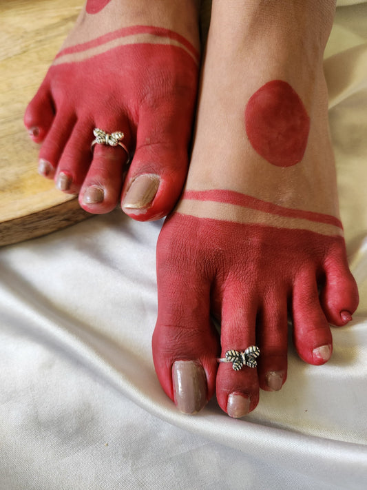 A pair of elegant silver toe rings with a polished finish, featuring delicate designs and an adjustable open band.