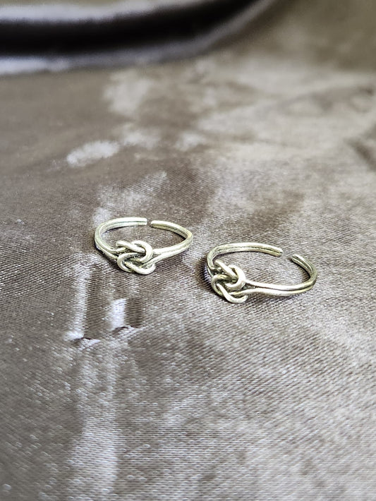 A pair of elegant silver toe rings with a polished finish, featuring delicate designs and an adjustable open band.