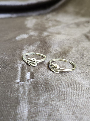 A pair of elegant silver toe rings with a polished finish, featuring delicate designs and an adjustable open band.
